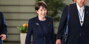 日本首相高市早苗出席公开活动，背景为日本国旗