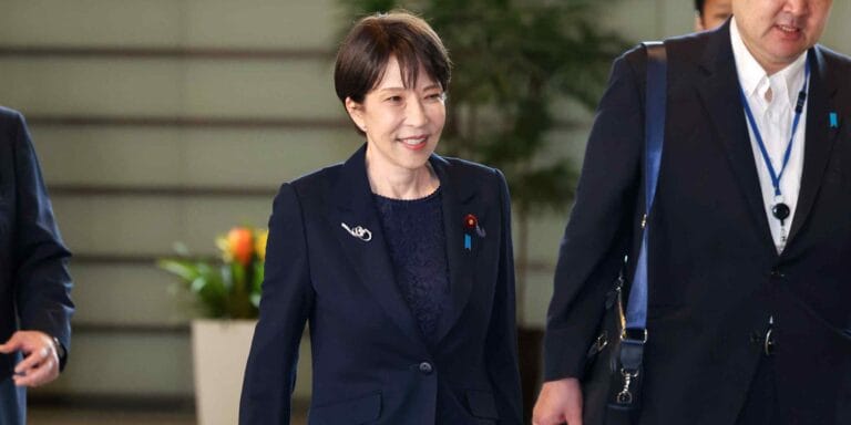 日本首相高市早苗出席公开活动,背景为日本国旗