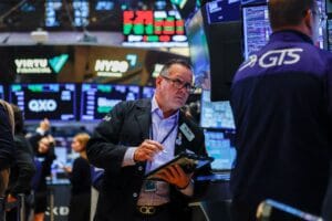 纽约证券交易所交易厅内，屏幕显示标普500和纳斯达克指数当日上涨，新闻滚动条提示9月非农就业数据低于预期