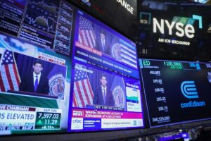 纽约证券交易所外景与美联储新任主席 Kevin Warsh 在 FOMC 会议后讲话的电视转播画面（Michael Nagle / Bloomberg 摄）